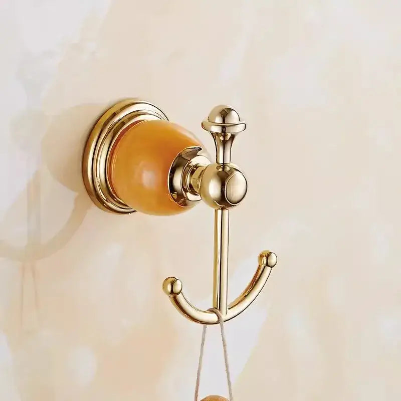 Ornate gold-toned wall-mounted hook with polished brass finish and amber ceramic accent from brass jade bathroom set