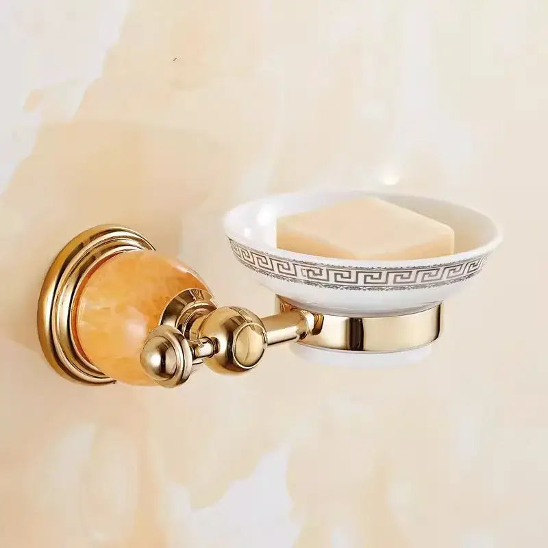 Gold-finished wall-mounted soap dish with white ceramic bowl black greek key trim and amber crystal accent in brass jade bathroom set