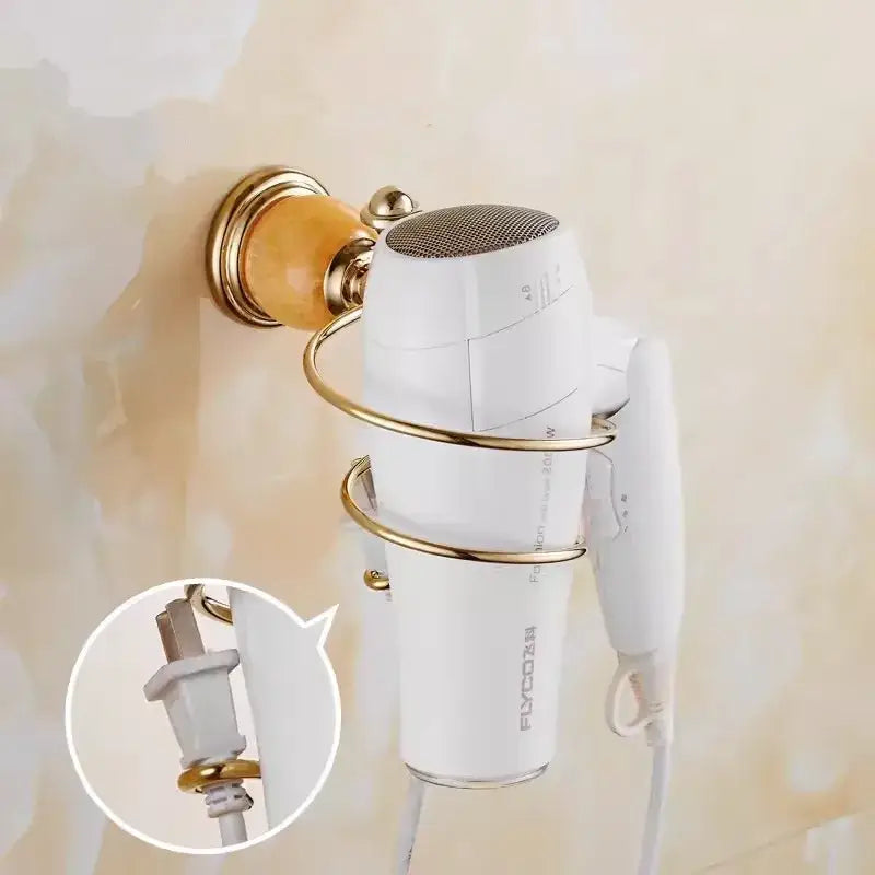 White flyco hair dryer mounted in gold-toned wall rack as part of ornate brass jade bathroom accessories set with amber accents