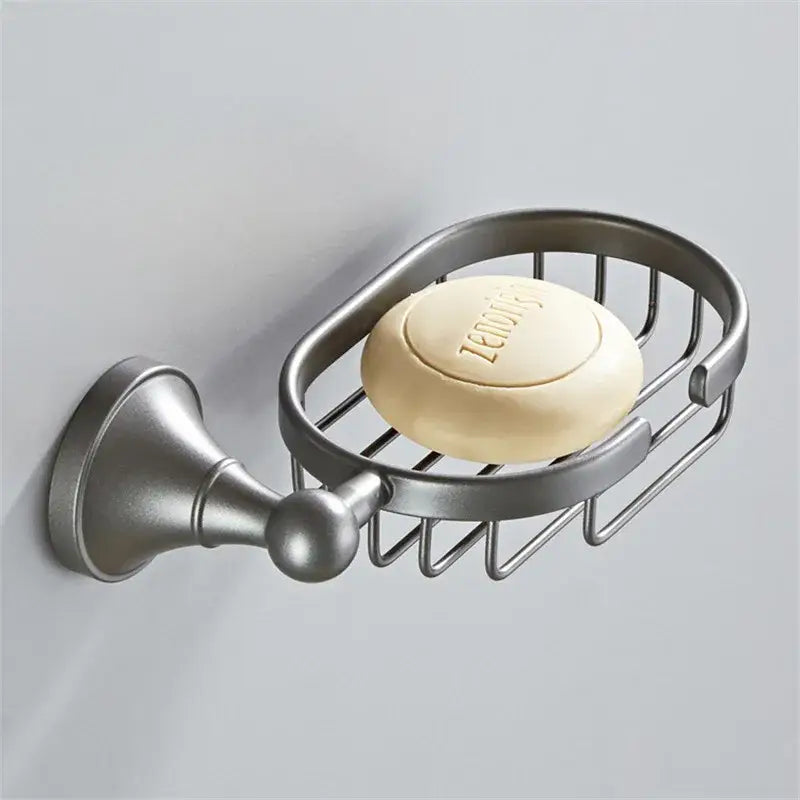 Ornate brushed nickel gray bathroom accessories set featuring a silver soap dish with wire mesh holding zenoys soap
