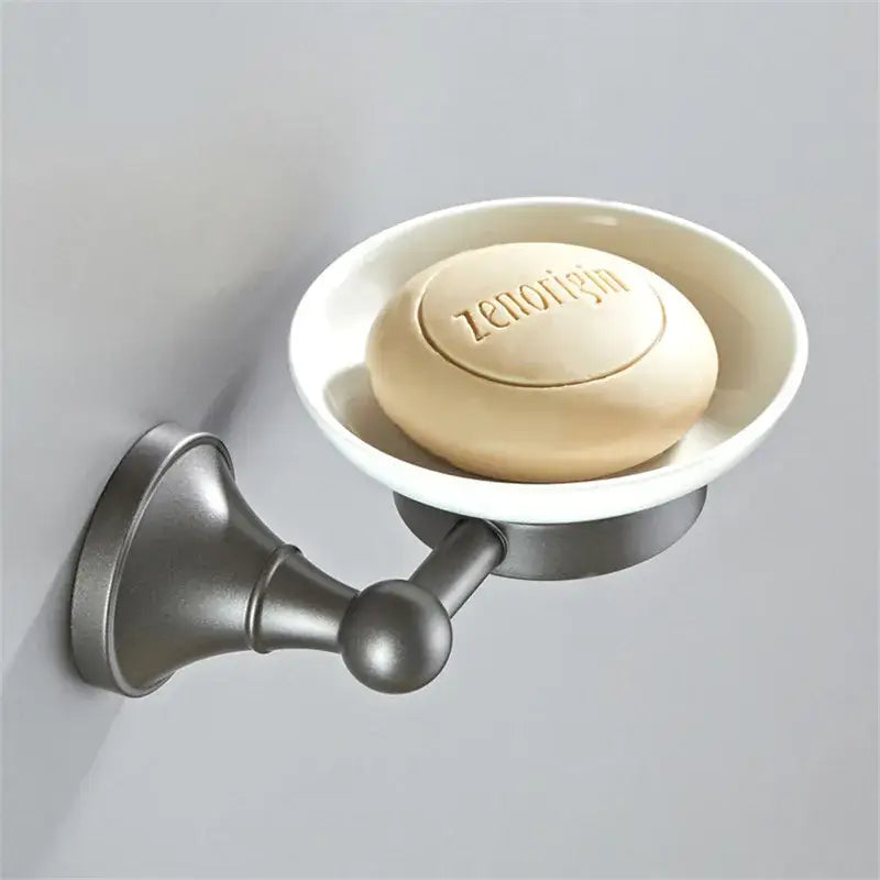 A matte bronze wall-mounted soap dish holding a beige zenorigin soap in the ornate brushed nickel gray bathroom accessories set