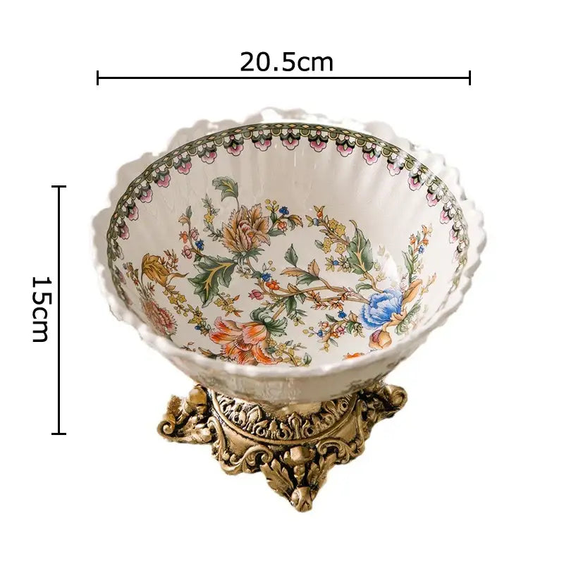 Ornate ceramic fruit bowl with a colorful flower pattern and scalloped rim on a gold metal stand for dining room use