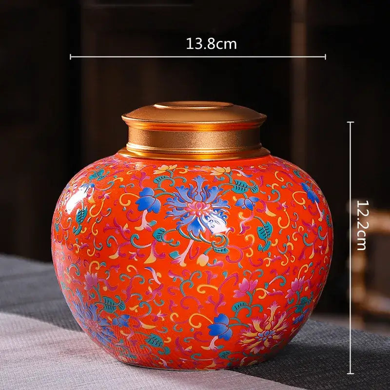 Vibrant orange ceramic storage jar with intricate blue pink gold floral patterns and polished brass lid for tea storage