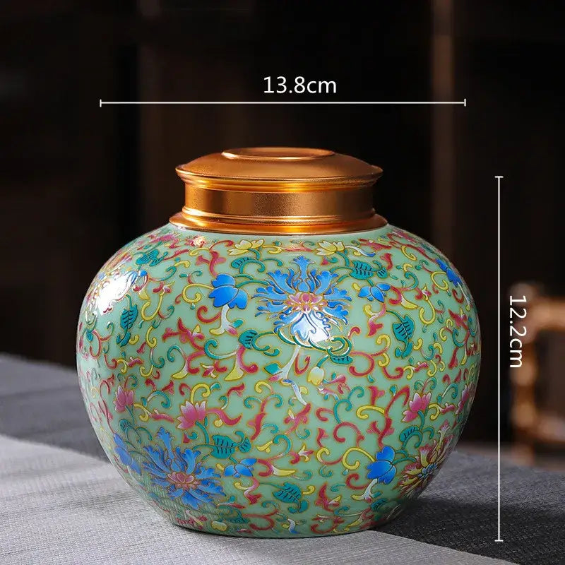 Ornate floral ceramic storage jar with gold-toned lid featuring blue pink and yellow patterns on light green glaze