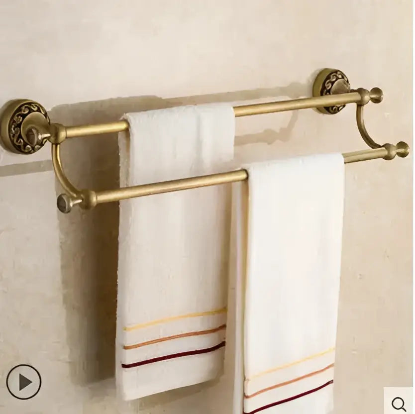 Brass double-bar towel rack with ornate end caps holding white towels in decorbites copper carved bathroom set