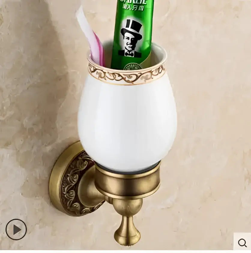 White ceramic toothbrush holder with gold-toned ornate copper carved metal base holding toothpaste and toothbrush decorbites copper carved bathroom accessories