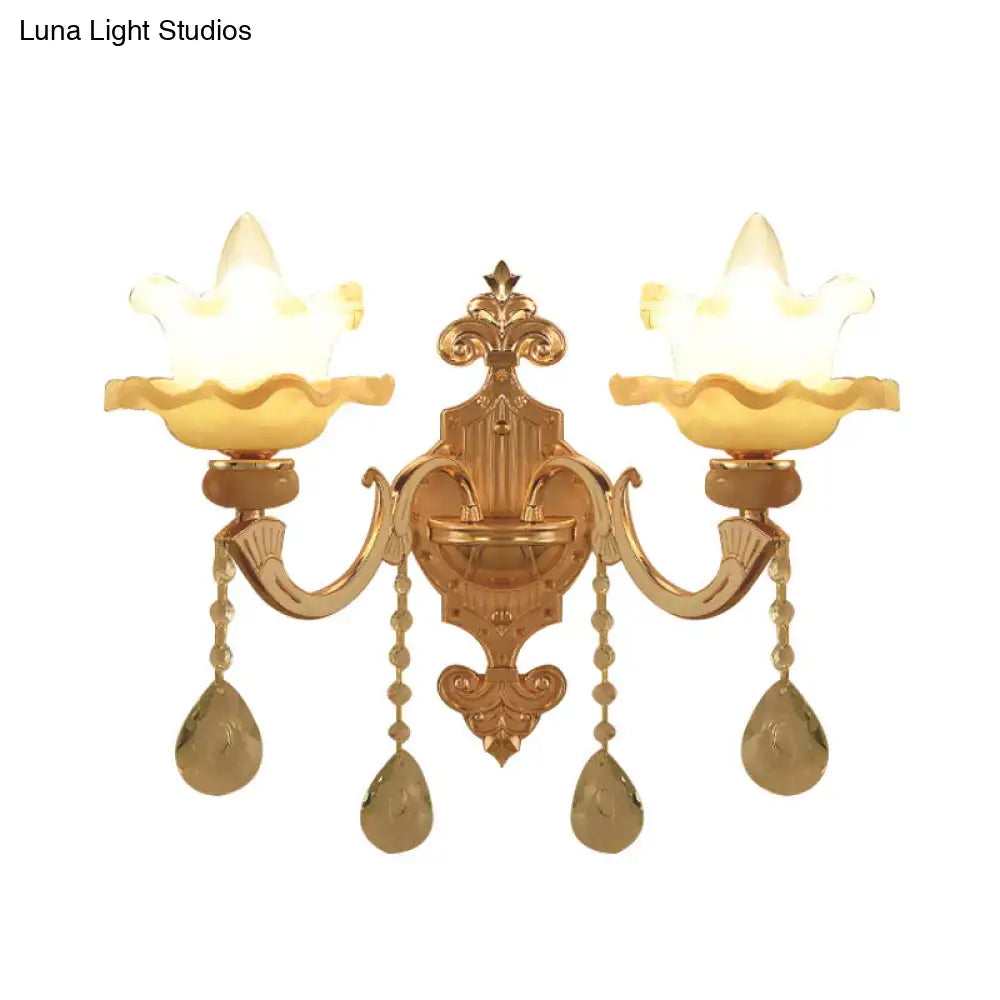 Ornate gold crystal wall sconce with two lotus-shaped frosted glass shades and dangling teardrop crystals for living room