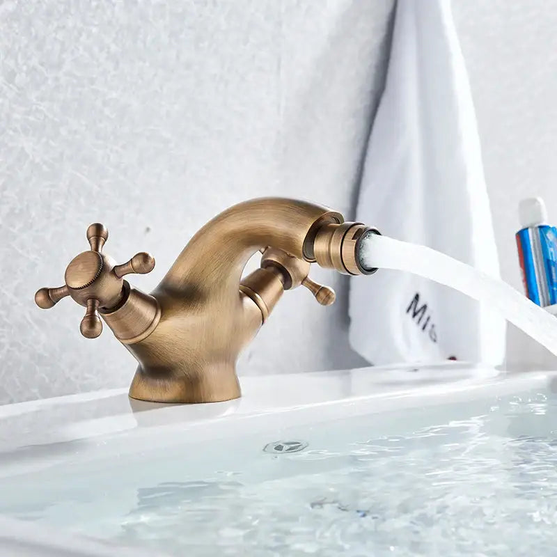 Antique brass-finished ornate gold dual handle bidet faucet with curved spout and cross handles by decorbites dual handle
