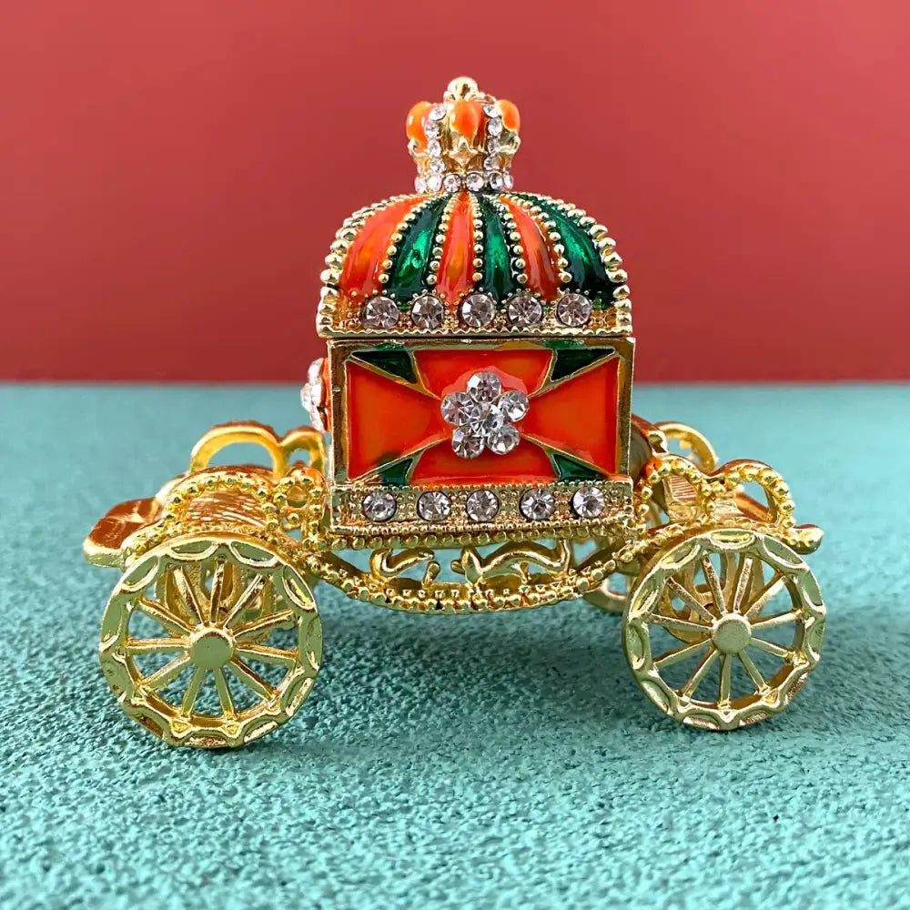 Ornate gold enamel crown jewelry box shaped as a carriage with red and green enamel and rhinestone accents
