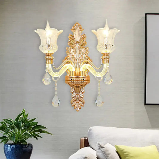 Ornate gold floral wall lamp with two frosted glass tulip shades and clear crystal glass teardrop accents for bedroom use