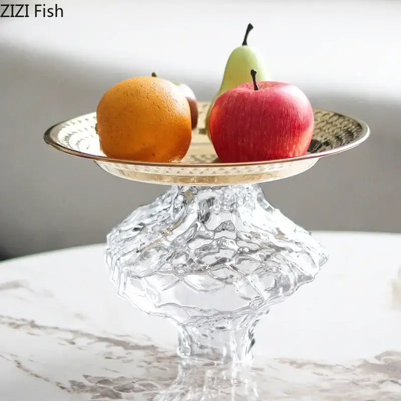 Clear glass fruits bowl with a gold-rimmed patterned plate on a pedestal for dining room dessert display