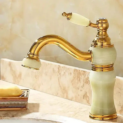 Ornate gold-finished bathroom basin sink faucet with curved spout and cream jade bathroom basin handle accents