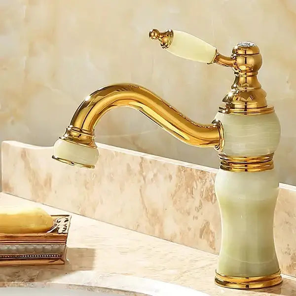 Ornate gold-finished bathroom basin sink faucet with curved spout and cream jade bathroom basin handle accents