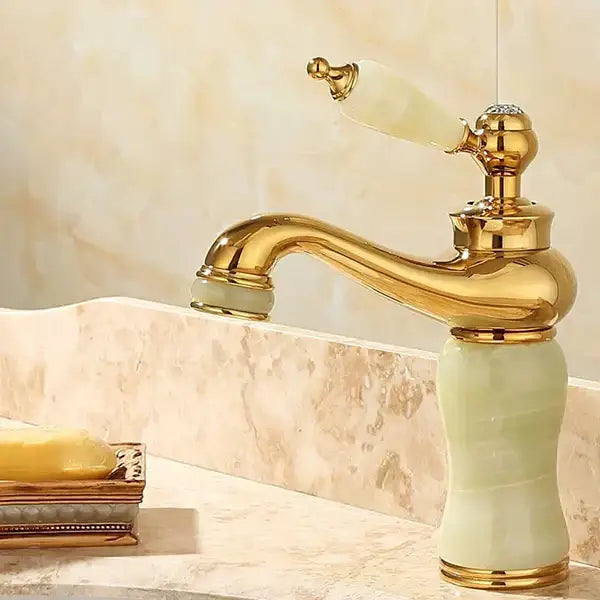 Ornate gold bathroom basin sink faucet with pale green jade handle and spout featuring detailed craftsmanship