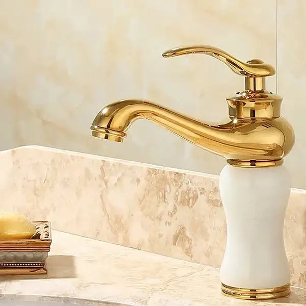 Ornate gold and green jade bathroom basin sink faucet with gold-finished curved spout and white ceramic base
