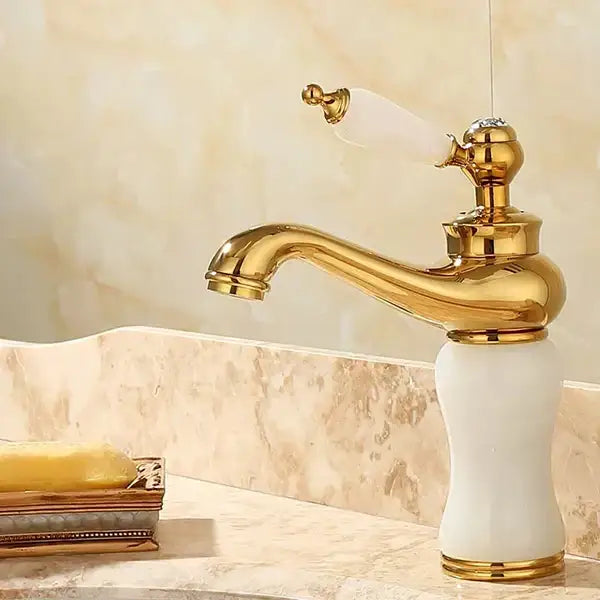 Ornate gold bathroom basin sink faucet with white ceramic base and handle featuring elegant curved spout for jade bathroom basin