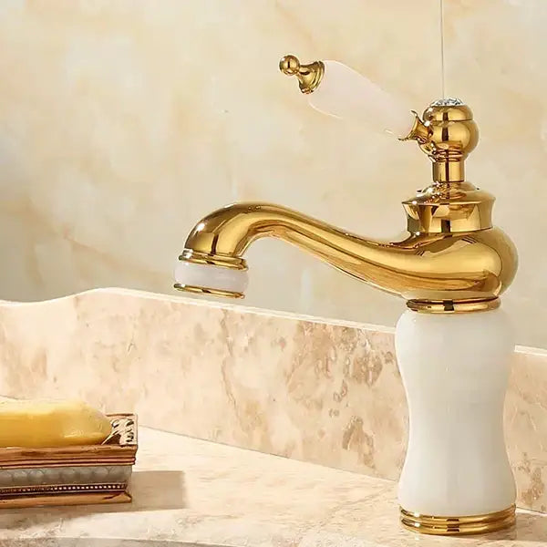 Ornate gold finished bathroom basin sink faucet with white ceramic handle and spout accents for jade bathroom basin