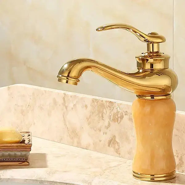 Ornate gold basin sink faucet with polished brass finish and amber-colored jade bathroom basin marble base
