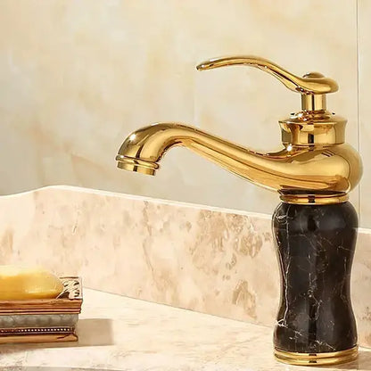Ornate gold basin sink faucet with a sleek curved spout and black marble base for jade bathroom basin use
