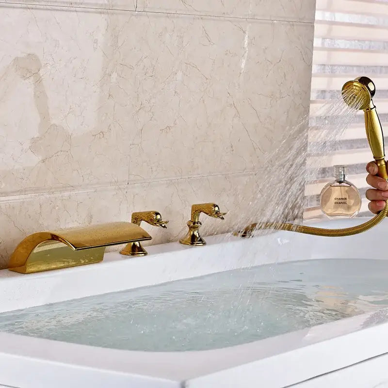 Ornate gold-toned bath tub faucet set with swan-shaped handles and matching handheld showerhead for bathroom use