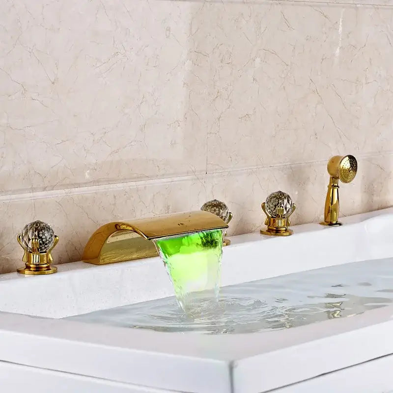 Ornate gold led waterfall bath tub faucet with glowing green illuminated spout and crystal handles for bathroom use