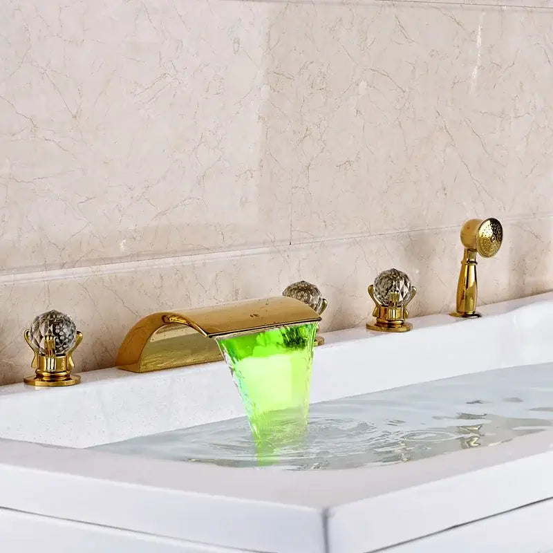 Ornate gold bath tub faucet with translucent green acrylic waterfall spout and crystal handles for bathroom use
