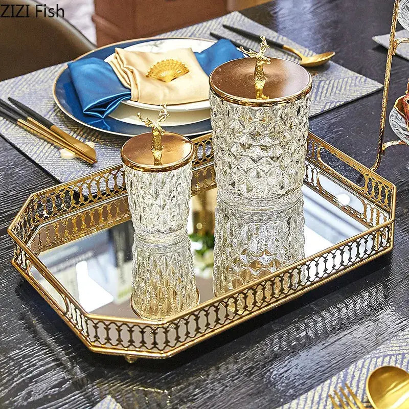 Ornate gold mirror glass storage tray with gold-trimmed edges holding faceted glass containers with gold deer finials