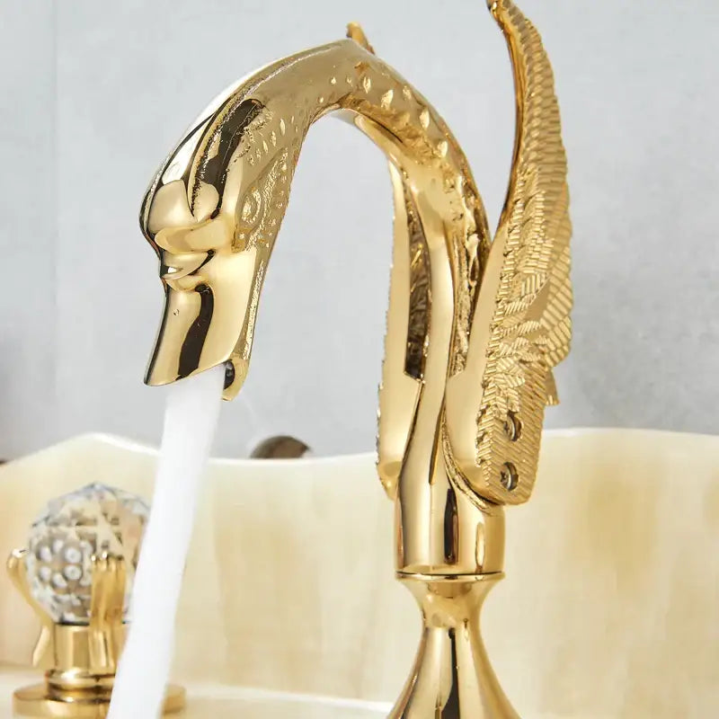 Ornate decorbites gold swan basin faucet with intricate feather detailing and crystal handles for bathroom use
