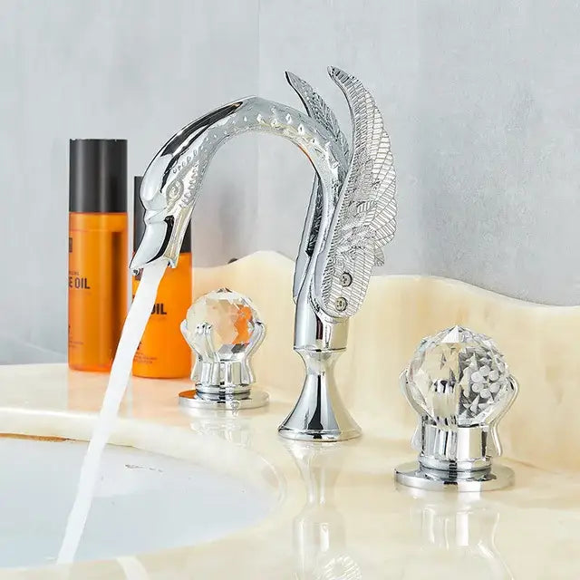 Ornate gold swan basin faucet with chrome finish and crystal knob handles featuring detailed feather decorbites gold swan design