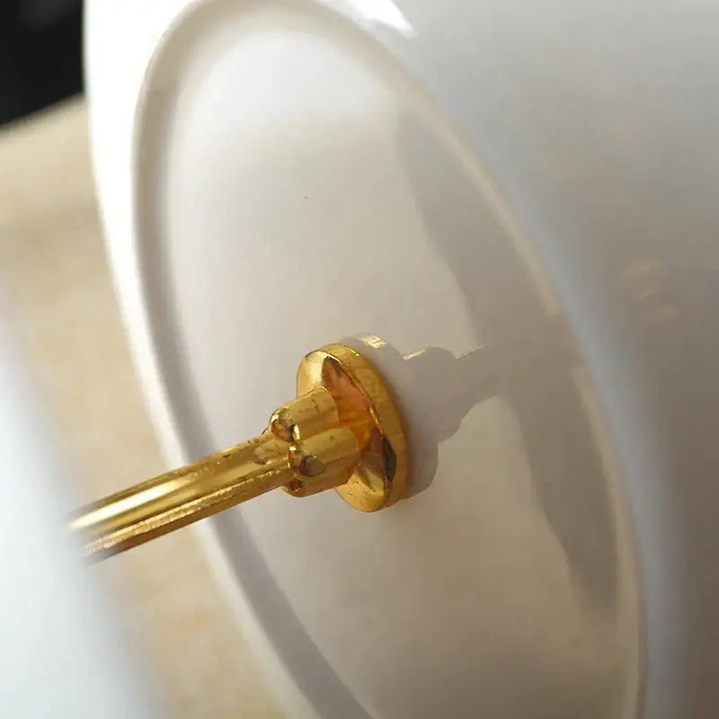 Gold-toned metal stem with circular base supports white ceramic plate in ornate gold three tiered floral fruit plates set