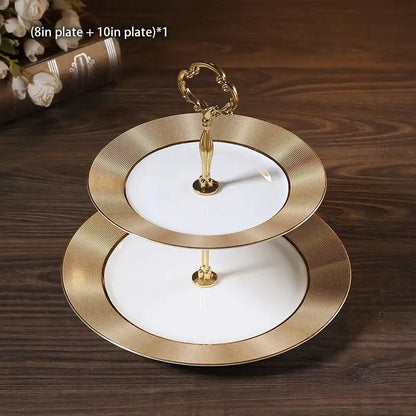 Elegant two-tiered white ceramic fruit plates set with gold-toned rims and ornate handles for dining room display
