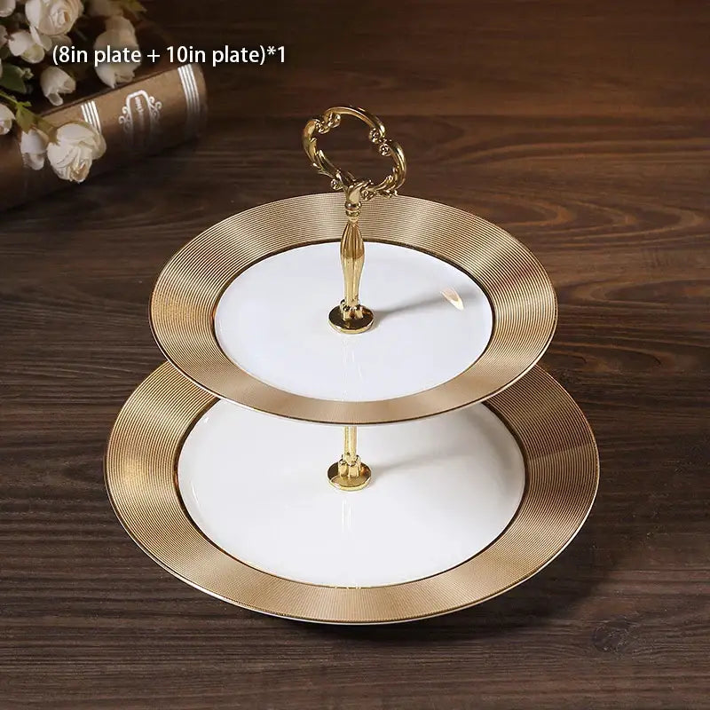 Elegant two-tiered white ceramic fruit plates set with gold-toned rims and ornate handles for dining room display