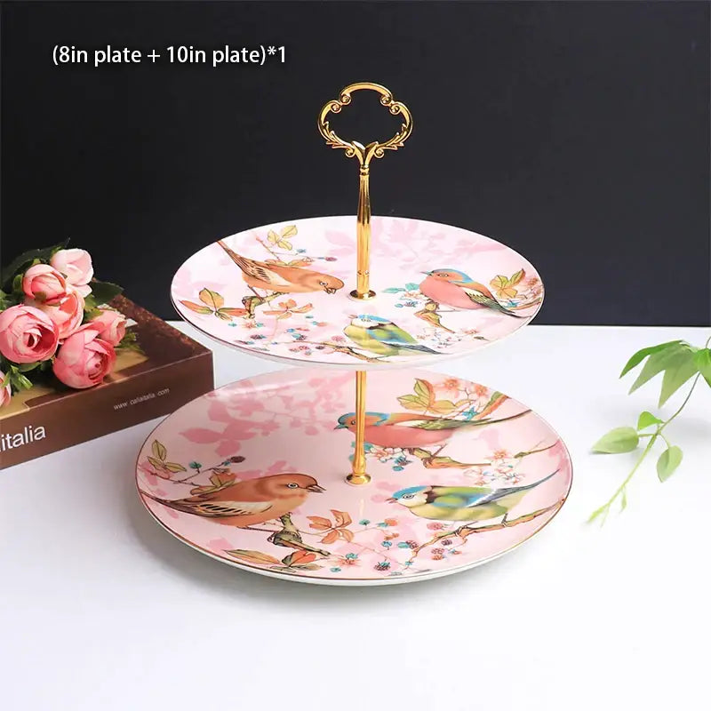 Pink ceramic two-tier fruit plates set with ornate gold handle and bird illustrations for dining room display