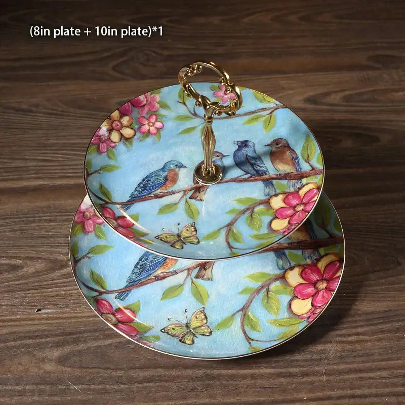 Ornate gold two-tiered fruit plates set with light blue ceramic painted birds and flowers with gold-toned handles