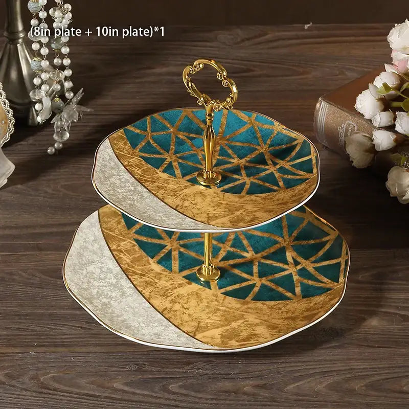 Ornate gold two-tiered fruit plates set with teal and gold geometric ceramic plates and golden ornate handle dining stand