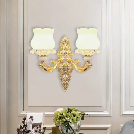Ornate gold wall light fixture with two frosted glass bloom shades designed for living room use with fixture width details