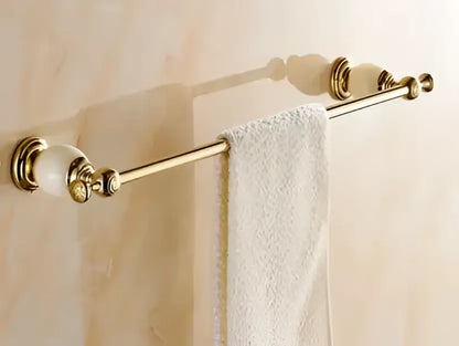 Ornate gold-toned towel rack with marble-like ceramic finials holding a white towel from decorbites brass jade hardware set