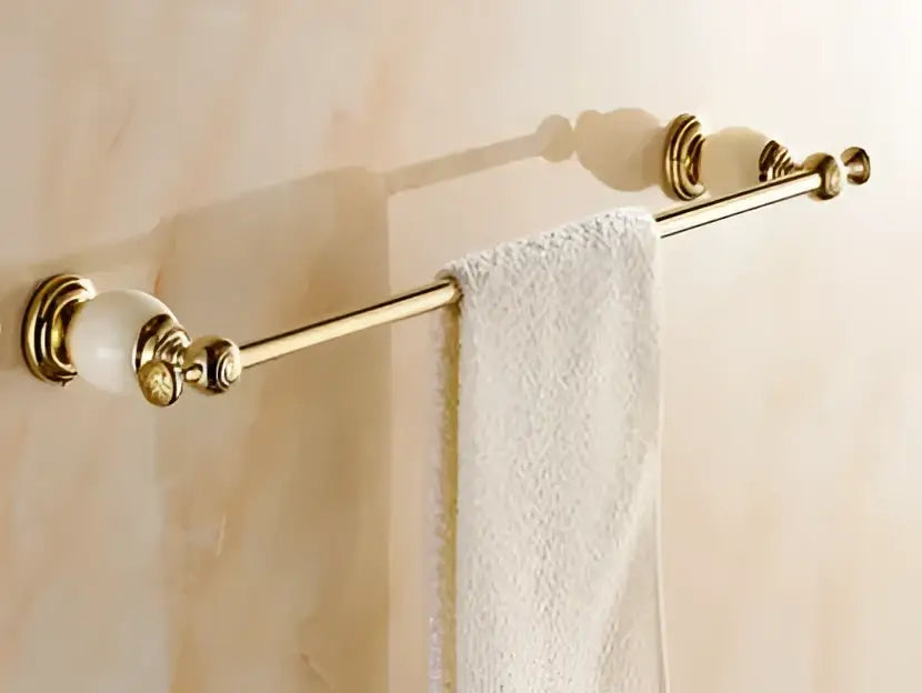 Ornate gold-toned towel rack with marble-like ceramic finials holding a white towel from decorbites brass jade hardware set