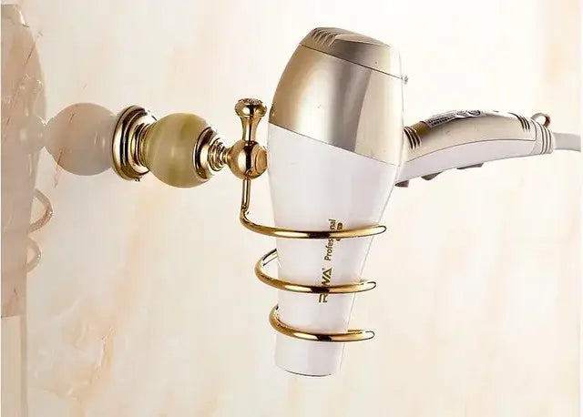 Gold-toned wall-mounted hair dryer holder with polished brass finish cradling white silver dryer from decorbites brass jade hardware set