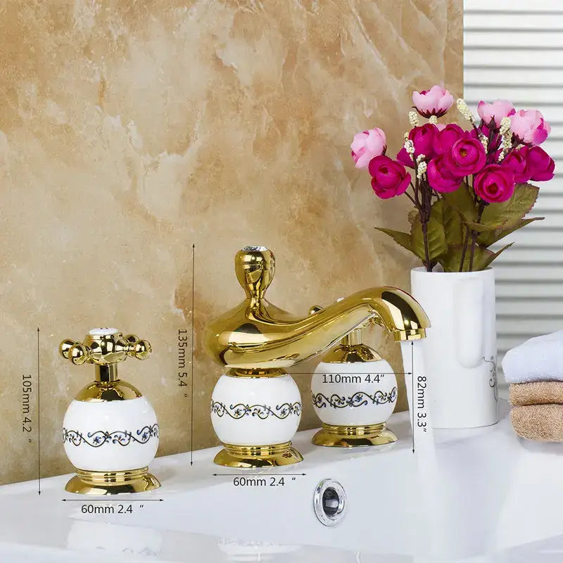 Ornate gold and white porcelain bathroom faucet set with black scrollwork detailing for a luxury faucet set