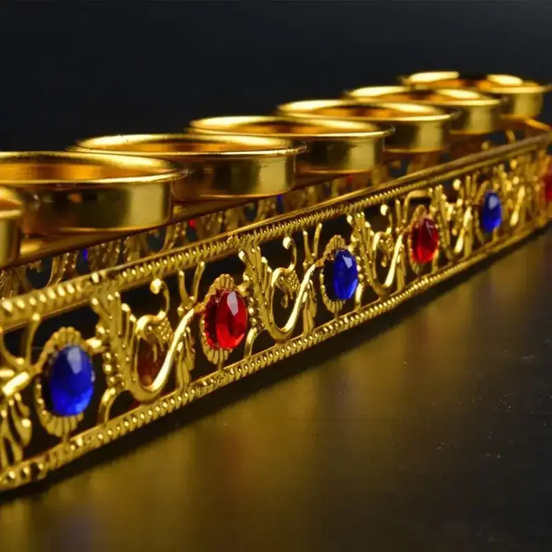 Ornate golden gem inlaid candlestick stand with intricate filigree and red and blue gemstones for wedding altar decor