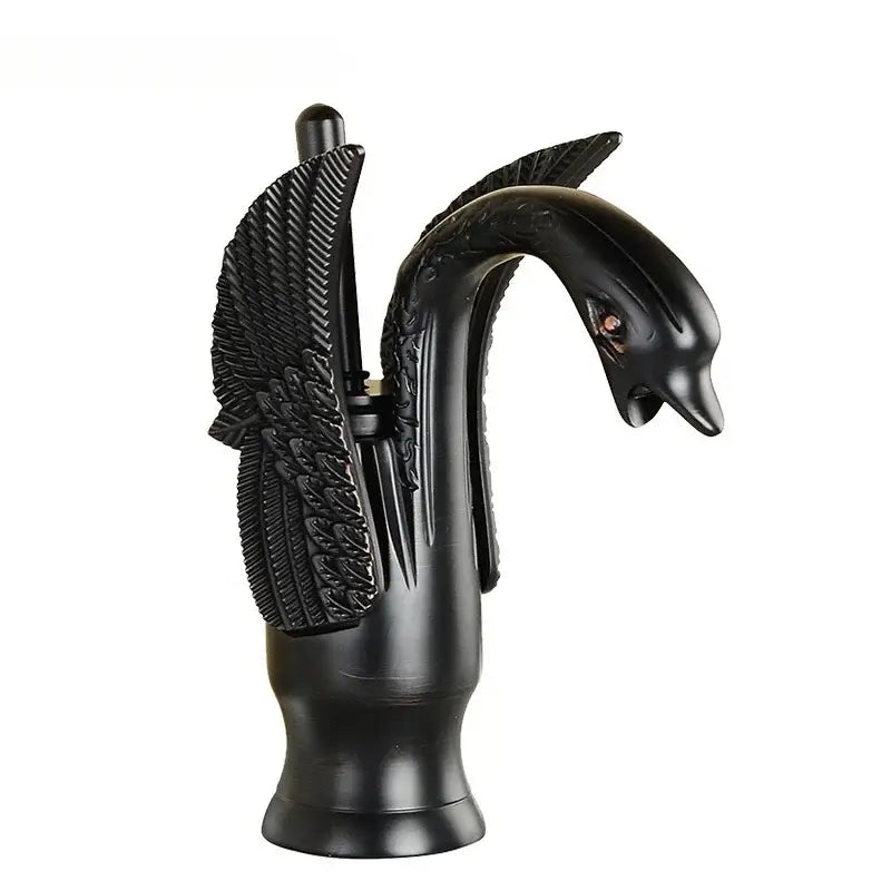 Black ornate swan-shaped fountain pen holder with detailed feather carvings and glossy finish beside solid brass basin faucet with ceramic valve core