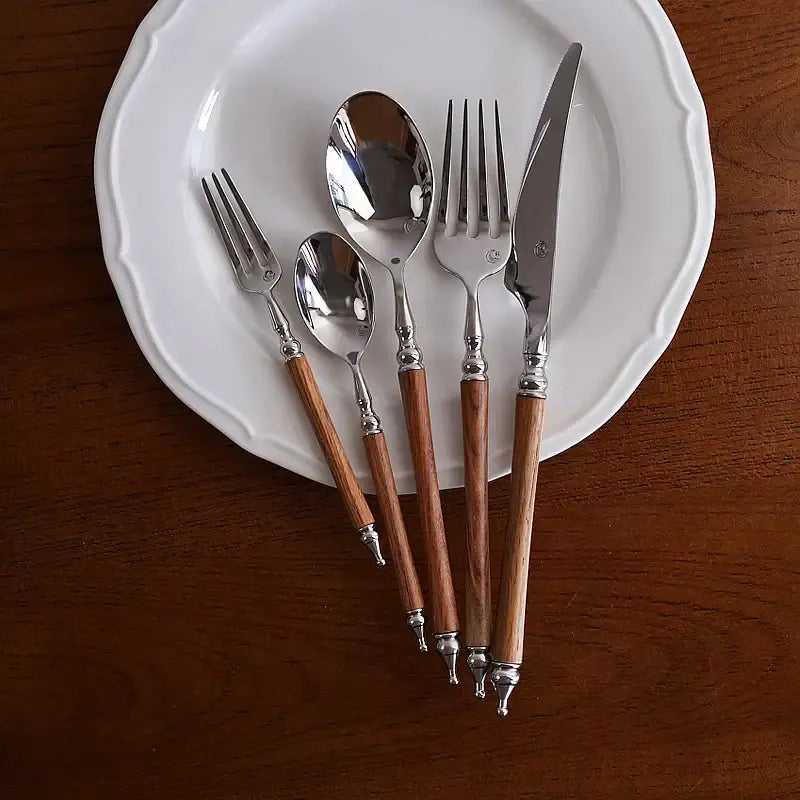 Ornate silver and wood stainless steel tableware set with polished metal heads and warm brown wooden handles for dining room