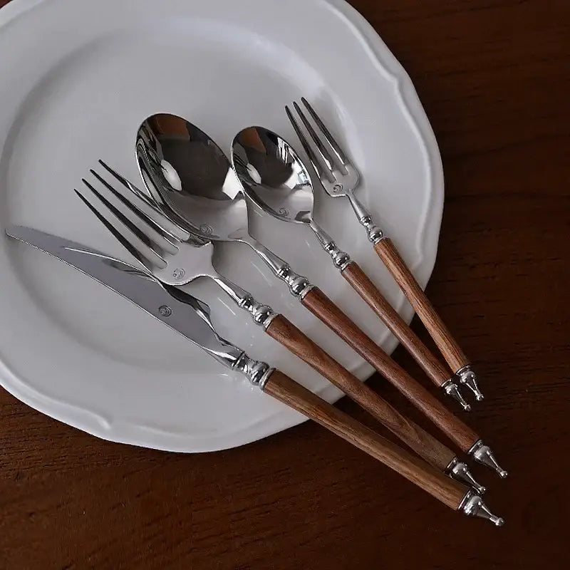 Ornate silver and wood stainless steel tableware set with polished metal heads and brown wooden handles for dining room use