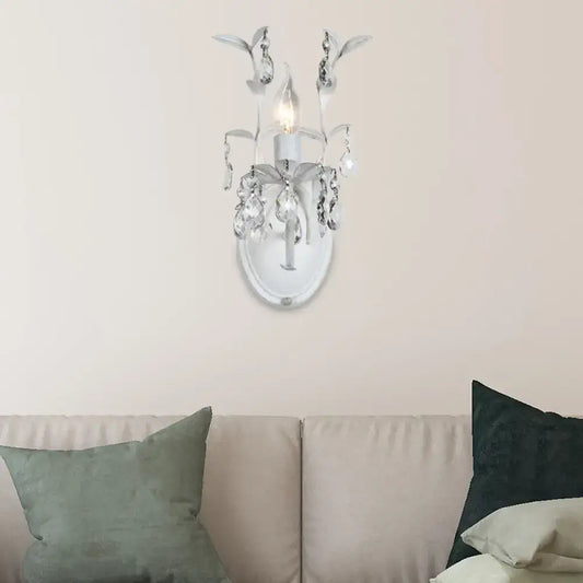 Ornate silver wall light fixture with crystal droplets and leaf embellishments designed for bedroom use