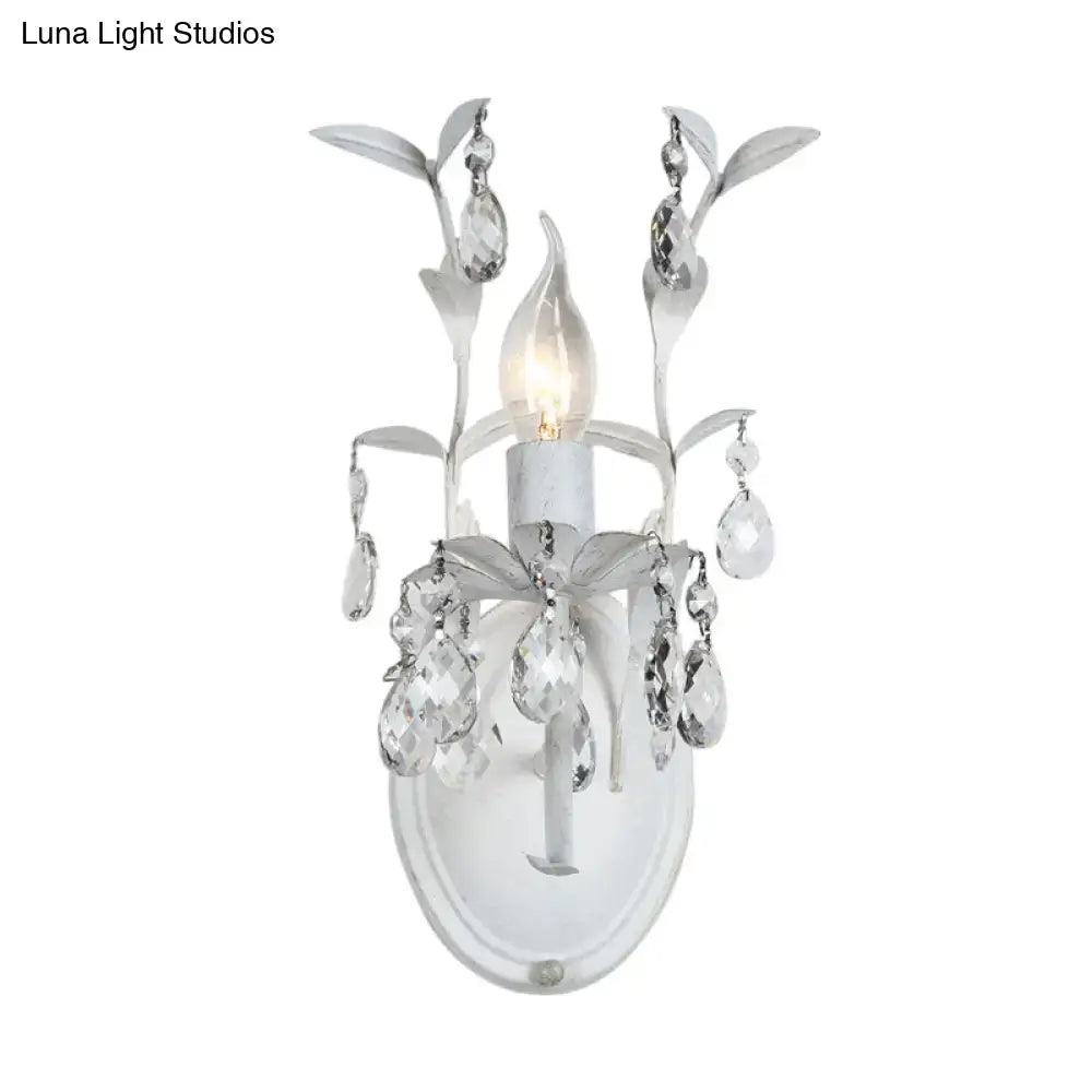 Elegant ornate silver leaf wall light fixture with dangling clear crystals and frosted glass for bedroom sconce lighting