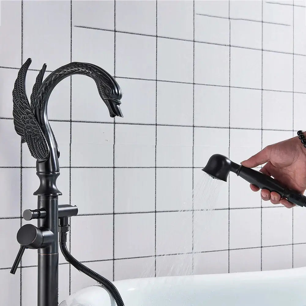Black swan-shaped black bathtub faucet with ornate winged design and matching handheld showerhead by decorbites