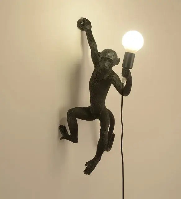 Black monkey wall lamp with textured matte finish holding exposed bulb in ornate white monkeys pendant chandelier for living room decor