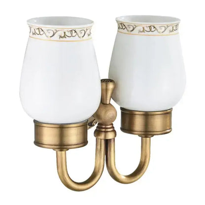 Antique brass two-light bathroom sconce with white ceramic shades and gold filigree detailing double cup holder