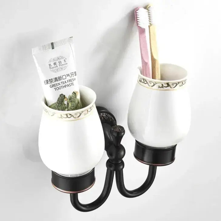 Ornate white ceramic double cup holder with black metal base for bathroom toothbrush stand use